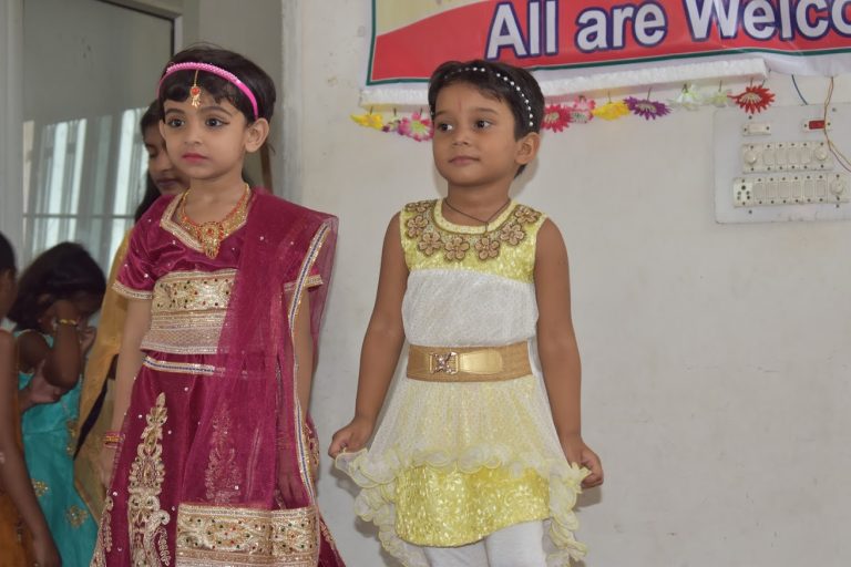 Young children in festive dress representing the school on stage during its foundation ceremony