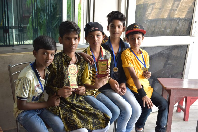 Group of students proudly holding awards while posing for a photo on stage during school’s foundation ceremony